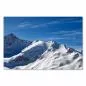 Preview: Gipfel schneebedeckter Berge ragen in den blauen Himmel mit leichten Wolken.