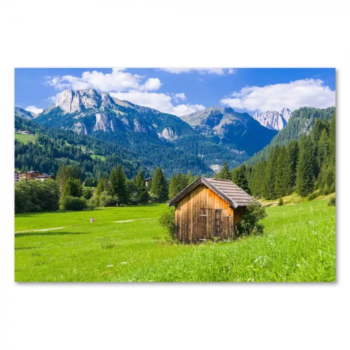 Holzhütte auf Wiese, Alpengipfel im Hintergrund, traumhafter Ausblick.