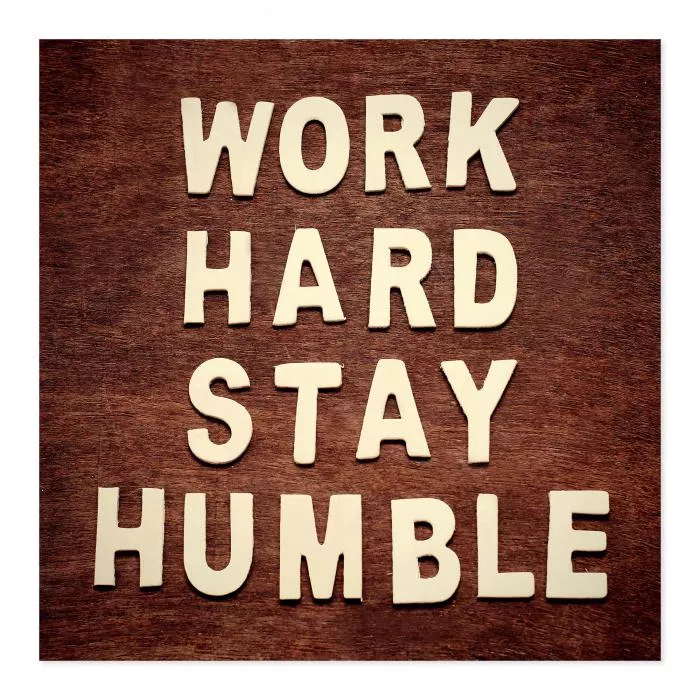 "Work hard, stay humble" - weiße Buchstaben auf Holz, Motivation & Bescheidenheit.