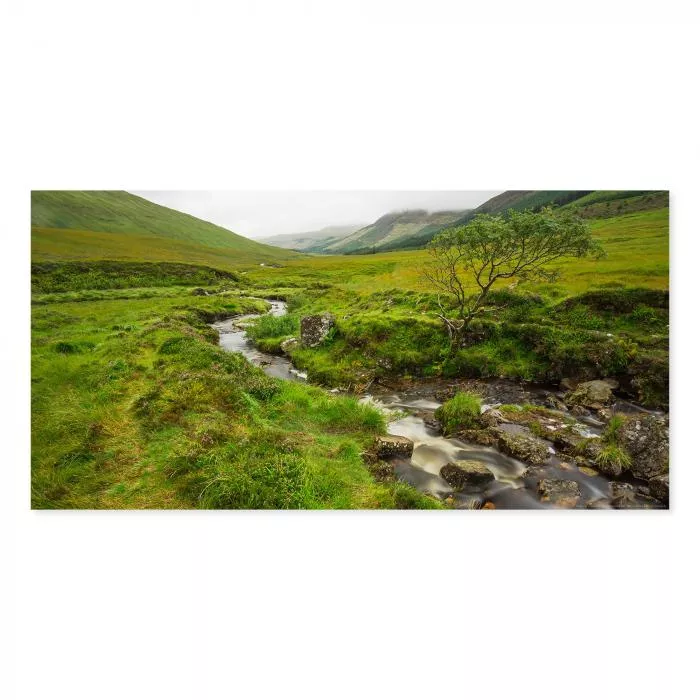 Idyllischer Bach schlängelt sich durch grüne Hügel der schottischen Highlands, ruhiger Ort in der Natur.