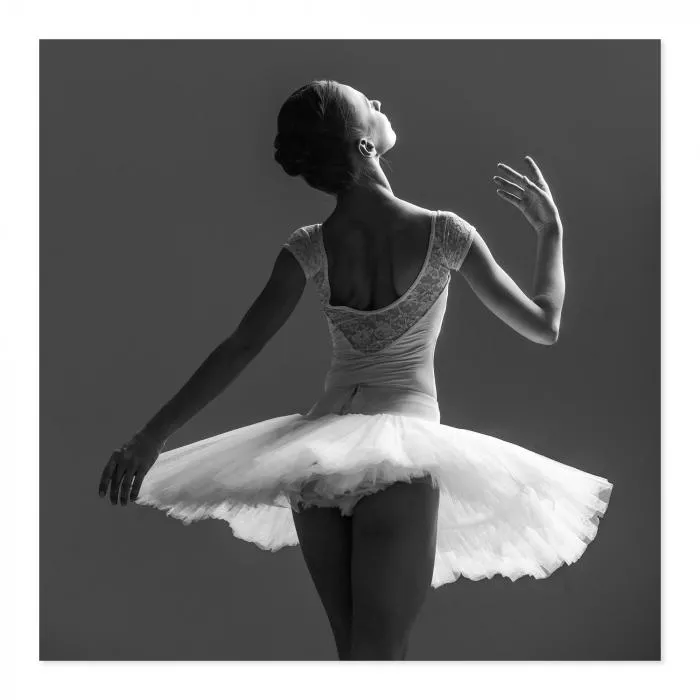 Schwarz-Weiß-Foto: Balletttänzerin (von hinten) im Tutu, Kopf elegant geneigt.