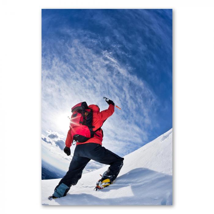 Mit Eispickel und Steigeisen ausgestattet, erklimmt ein Bergsteiger einen verschneiten Gipfel unter strahlend blauem Himmel.