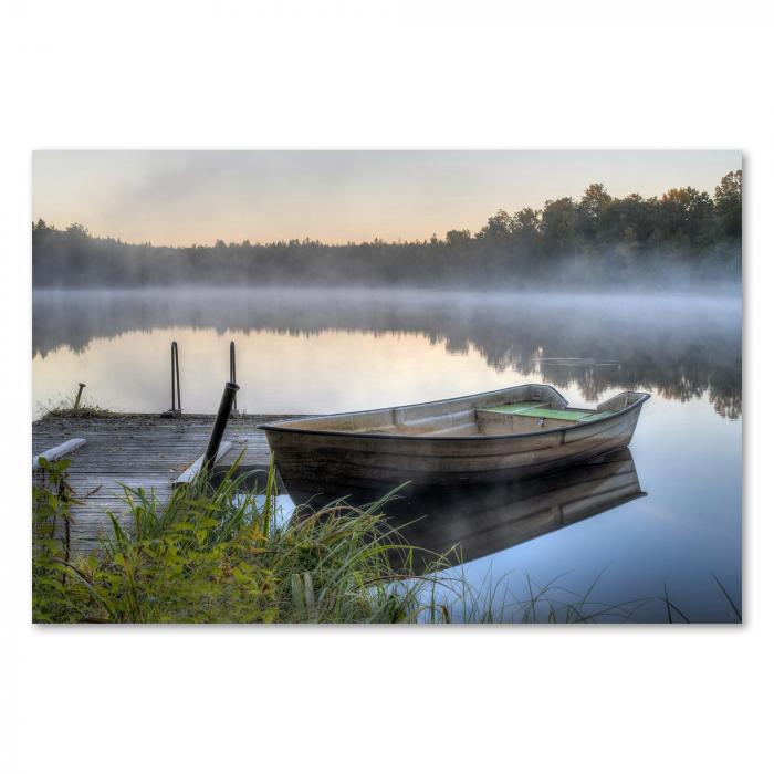 Einsames Holzboot am Steg, Morgennebel schafft friedliche Atmosphäre über dem Wasser.