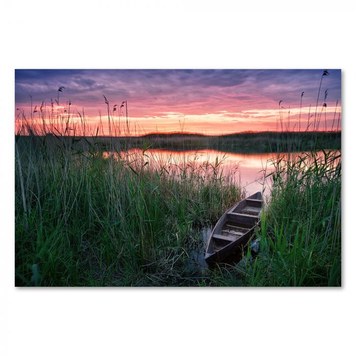 Holzboot am Seeufer, farbenfroher Sonnenuntergang, Spiegelung im Wasser.