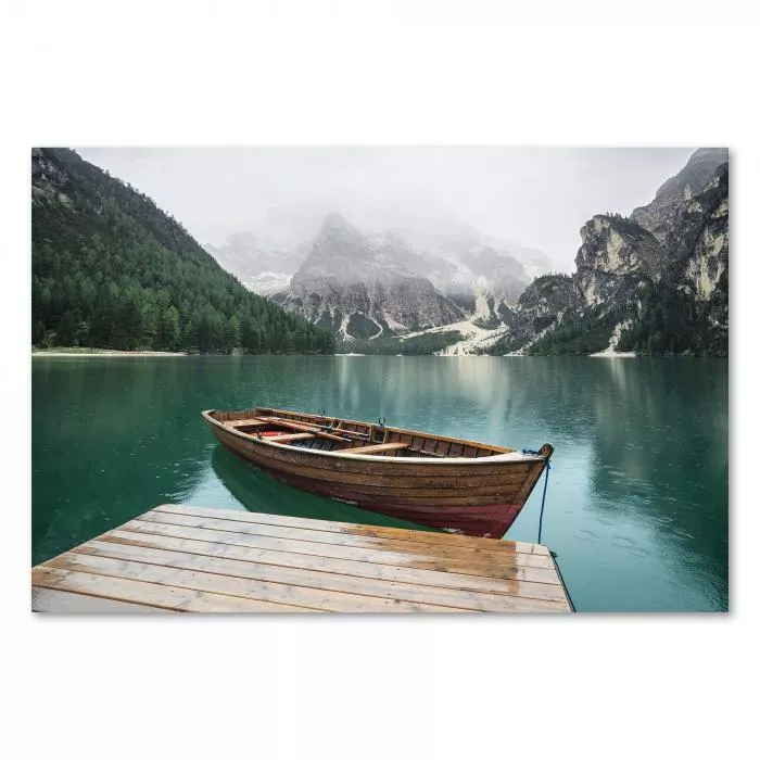 Holzsteg, Holzboot auf Bergsee, majestätische Berge, bewölkter Himmel.