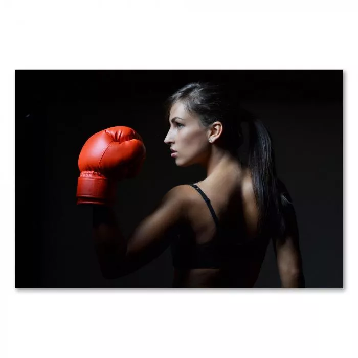 Eine starke Frau beim Boxtraining – ihr Blick drückt Entschlossenheit und Kraft aus.