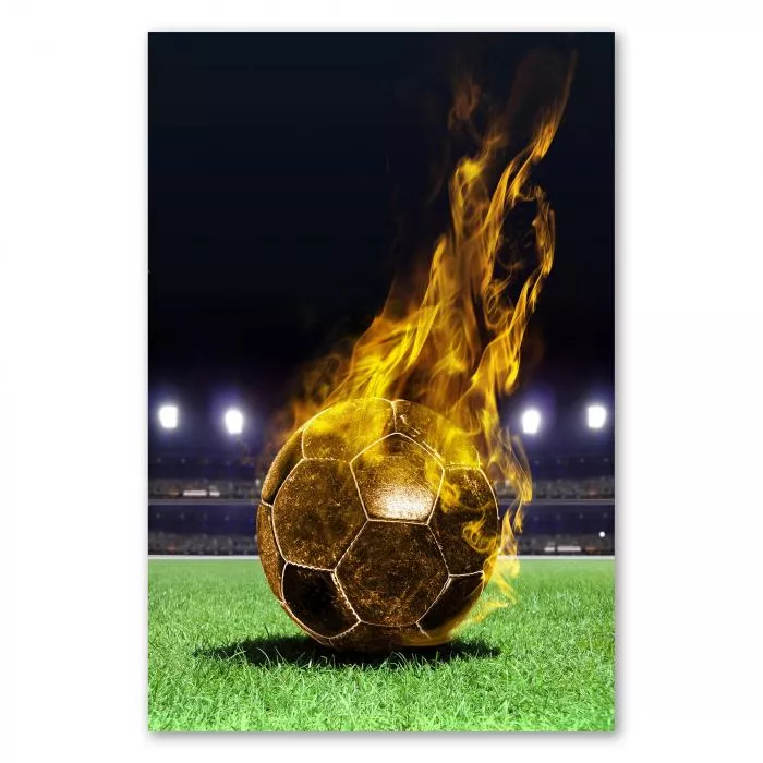 Ein Fußball in Flammen liegt auf dem Rasen eines Fußballstadions bei Nacht.