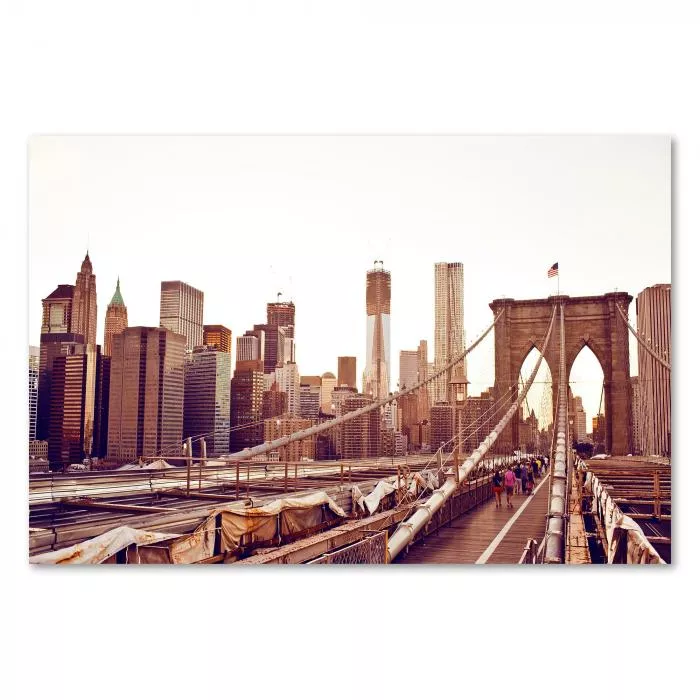 Panoramablick von der Brooklyn Bridge auf die Skyline von Manhattan im warmen Abendlicht.