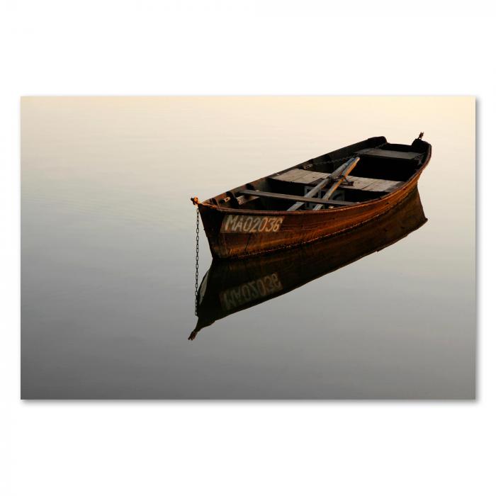 Ein kleines, altes Holzboot liegt ruhig auf dem Wasser und spiegelt sich im stillen See wider.