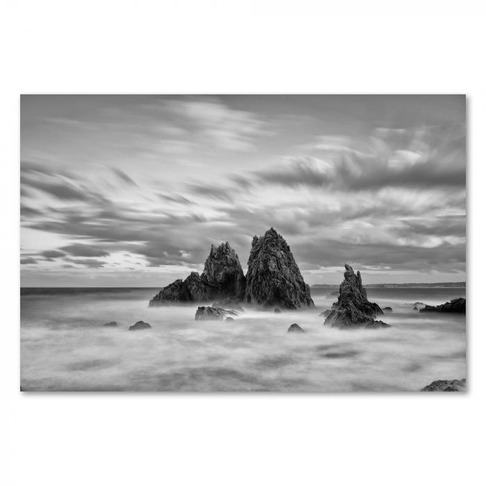 Schwarz-Weiß-Foto: Drei Felsen im Meer, Wellen, Wolken, Langzeitbelichtung.