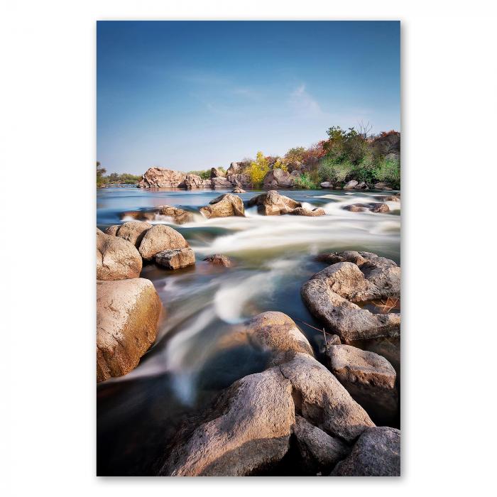 Langzeitbelichtung: Fluss schlängelt sich durch Felsen, warme Lichtstimmung.