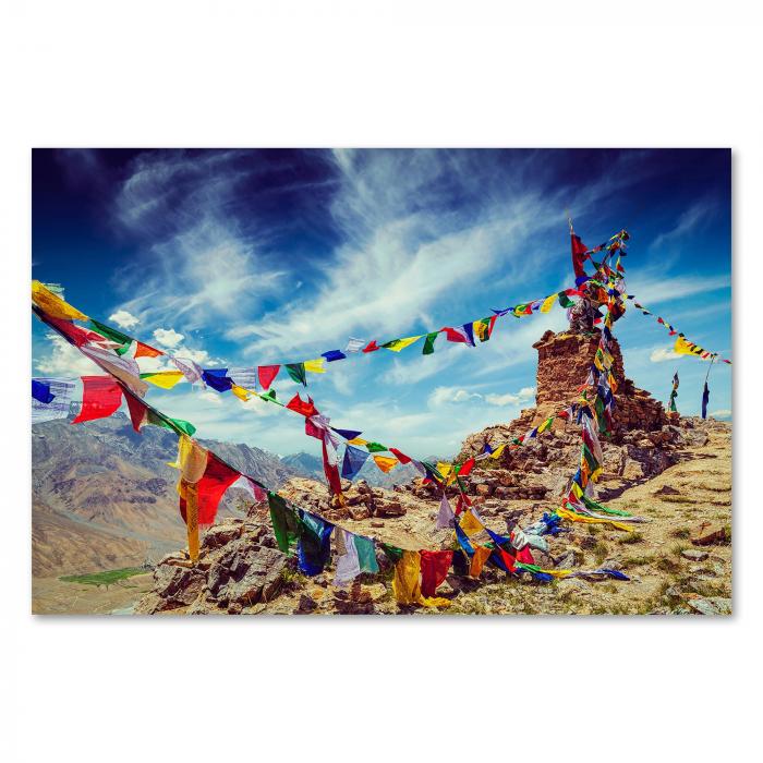 Bunte Gebetsfahnen flattern im Wind vor einem alten Steinturm im Himalaya Gebirge. Die leuchtenden Farben symbolisieren Glück & Frieden.