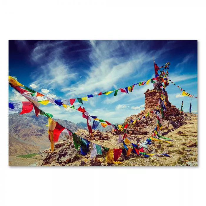 Bunte Gebetsfahnen flattern im Wind vor einem alten Steinturm im Himalaya Gebirge. Die leuchtenden Farben symbolisieren Glück & Frieden.