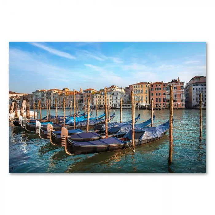 Gondeln liegen am Ufer eines Kanals in Venedig, farbenfrohe Häuserfassaden im Hintergrund.