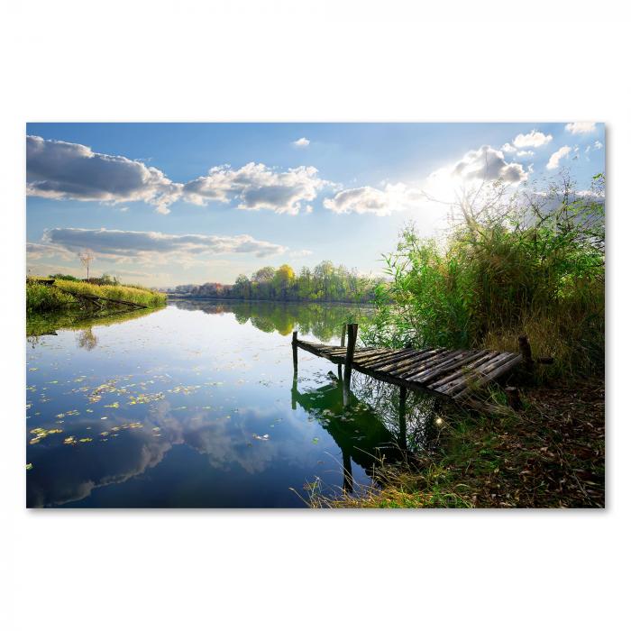 Holzsteg, ruhiger See, herbstlich buntes Laub, Sonnenspiegelung im Wasser.