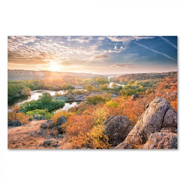 Sonnenaufgang über Fluss in Herbstlandschaft, Felsen im Vordergrund, warmes Licht.