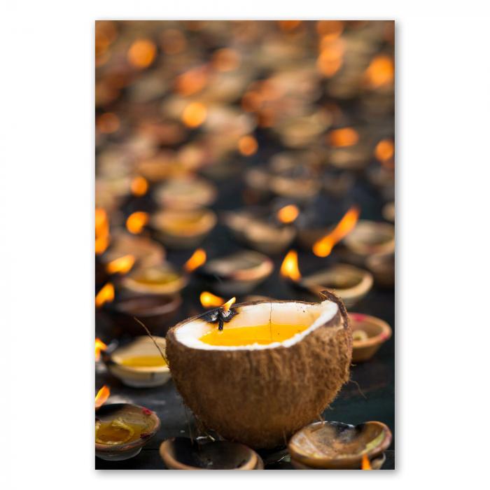 Brennende Kokosnuss-Öllampe steht zwischen anderen Lampen, warmes Licht im Tempel in Sri Lanka.