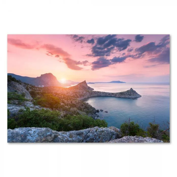 Die Sonne geht hinter schroffen Felsen auf und taucht das Meer in warme Farben. Ein atemberaubender Anblick, der die Schönheit der Natur zeigt.