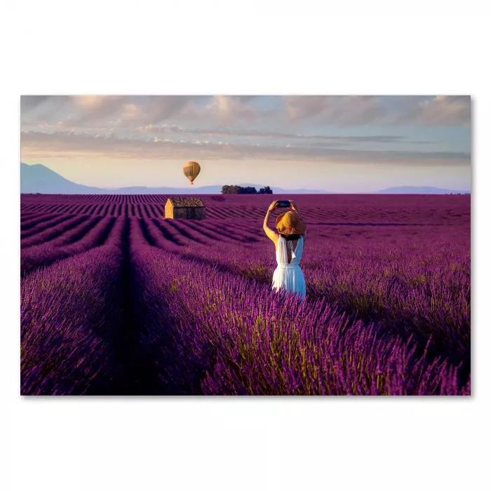 Frau in Weiß, Sonnenhut, fotografiert Lavendelfeld, Heißluftballon am Horizont.