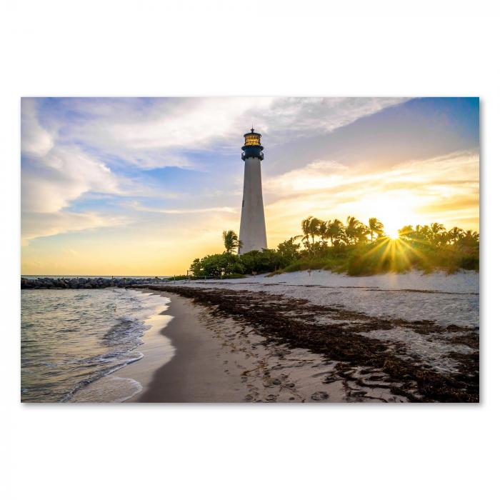 Sonnenaufgang am Strand, Leuchtturm im Hintergrund, Palmen & goldenes Licht.