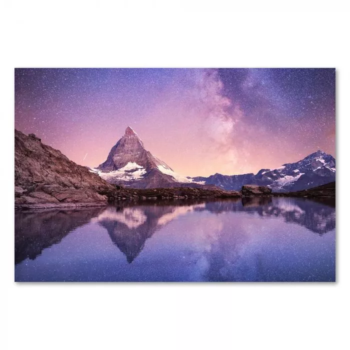 Das Matterhorn spiegelt sich im stillen Wasser eines Bergsees. Über dem Gipfel leuchtet die Milchstraße am Nachthimmel. Ein magischer und atemberaubender Anblick.