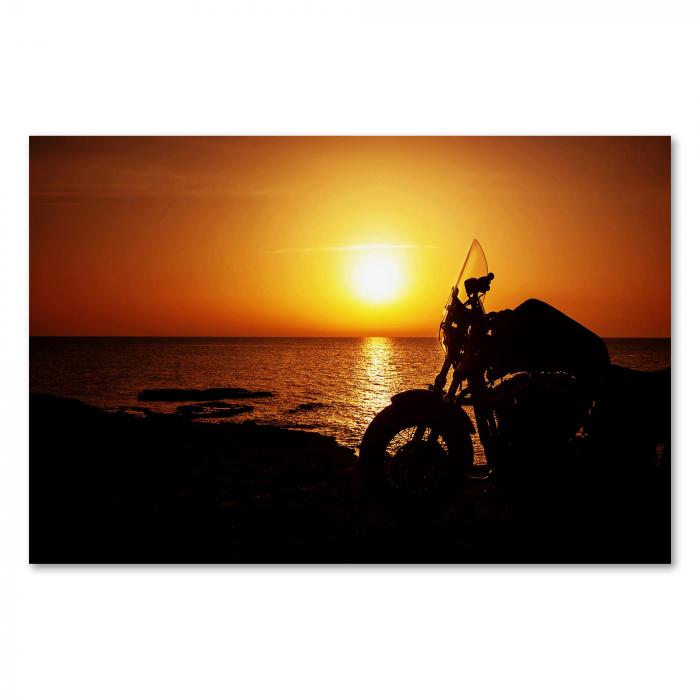 Freiheit pur: Ein Motorrad am Meer, die Silhouette vor dem Sonnenuntergang vermittelt Abenteuerlust.