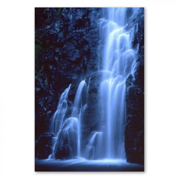 Wasserfall in der Nacht erstrahlt in bläulichem Licht, das Wasser wirkt wie flüssiges Silber.