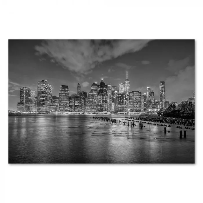 Skyline von New York City bei Nacht, Lichter spiegeln sich im Wasser.