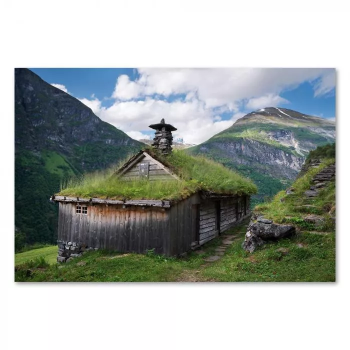 Traditionelles norwegisches Bauernhaus mit Grasdach, Berge im Hintergrund.