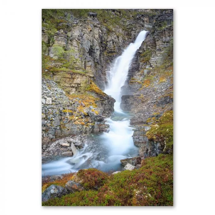 Wasserfall stürzt über Felsen in smaragdgrünes Becken, umgeben von Vegetation und schroffen Wänden.