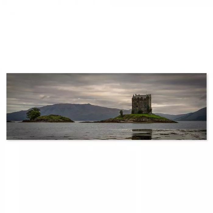 Malerische Insellandschaft in Schottland mit historischem Schloss, majestätische Berge erheben sich im Hintergrund.