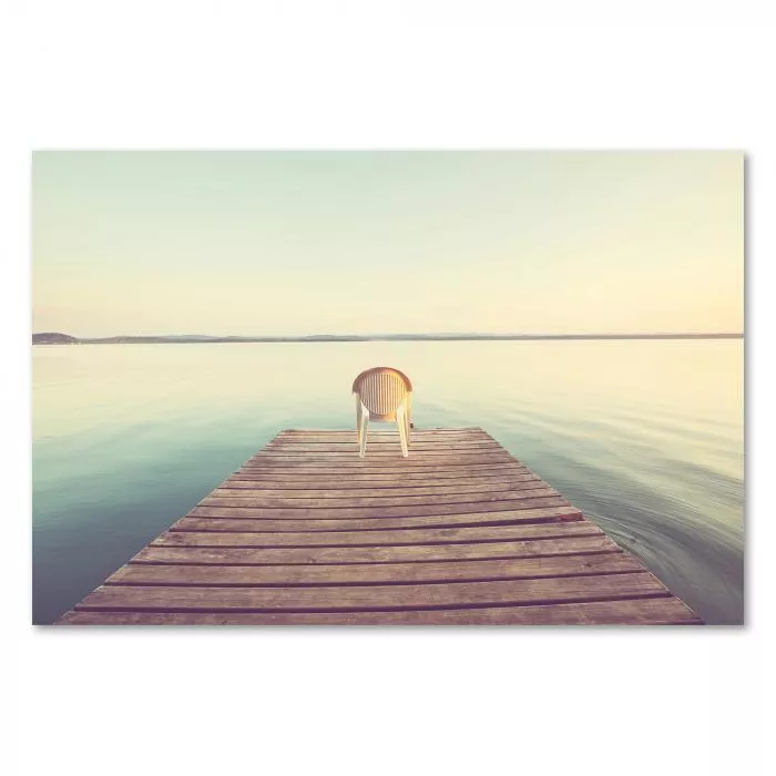 Ein einsamer Stuhl auf einem Steg am See - ein Ort der Ruhe und Entspannung.