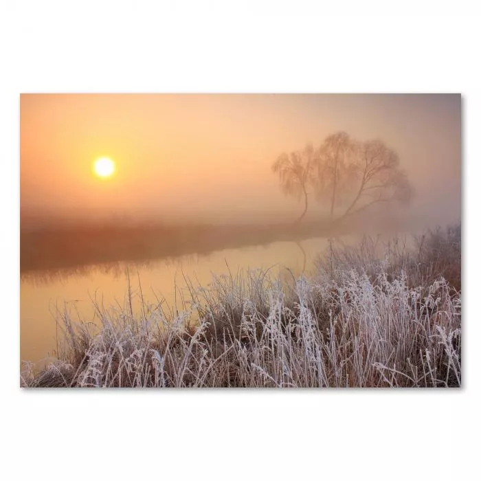 Die Sonne bricht durch den Nebel und erzeugt eine mystische Stimmung am Fluss.