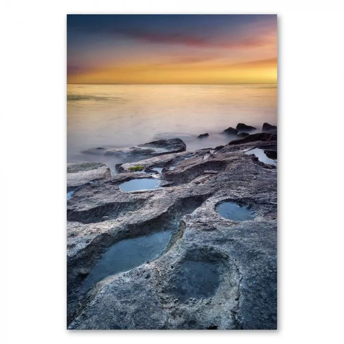 Felsiger Strand, Wasserlöcher, Meer & farbenfroher Sonnenuntergang im Hintergrund.