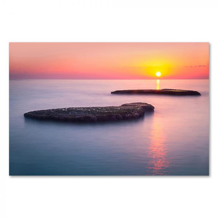 Zwei Felsen im Meer, die Sonne versinkt am Horizont - ein romantischer Sonnenuntergang.