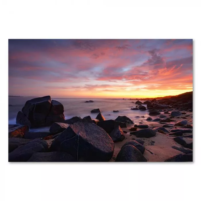 Sonnenuntergang, warme Farben, Felsen am Strand, ruhiges Meer.