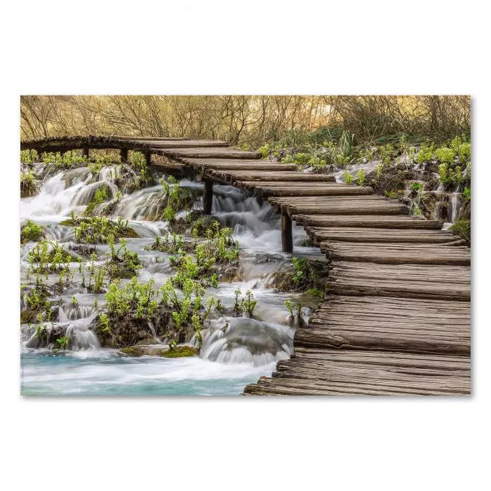 Holzsteg über einen kleinen Wasserfall im Wald, das Wasser und das Grün schaffen Ruhe und Besinnlichkeit.