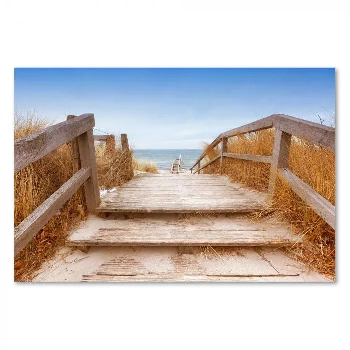 Ein Holzsteg führt durch schneebedeckte Dünen zum Strand - ein Wintermotiv voller Ruhe.