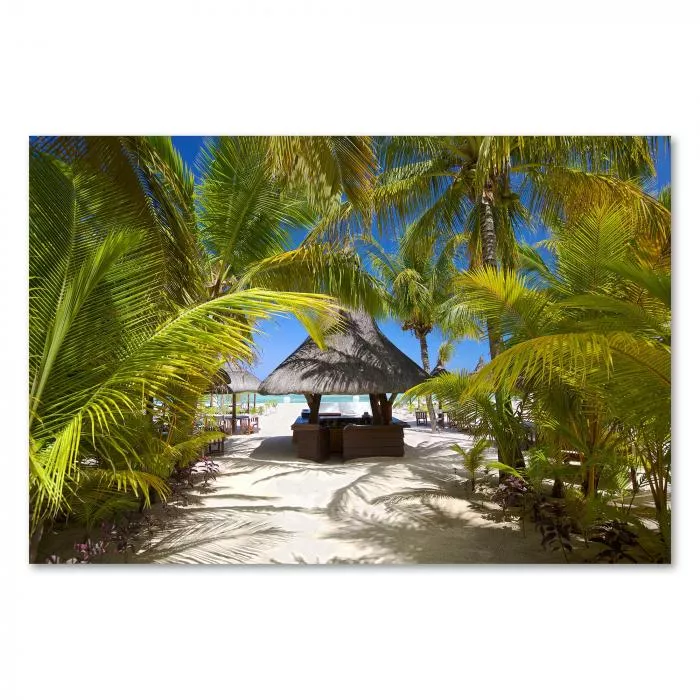 Eine Strandbar mit Strohdach zwischen Palmen und weißem Sandstrand. Im Hintergrund das blaue Meer.