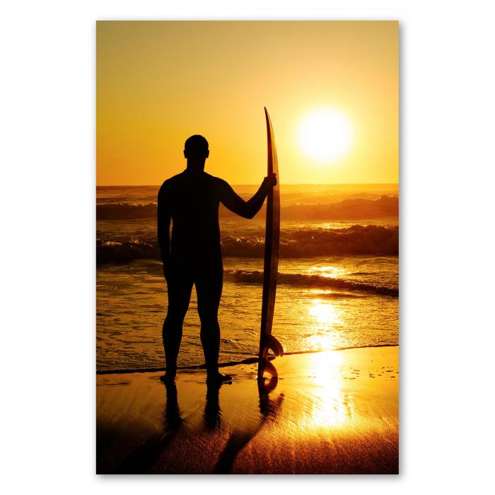 Die Silhouette eines Surfers mit Surfbrett steht am Strand und blickt auf den Sonnenuntergang über dem Meer.