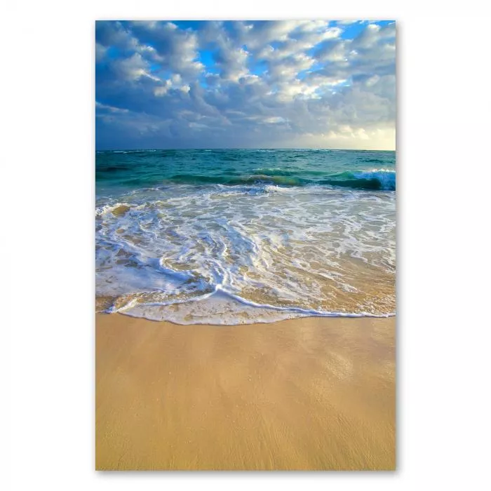 Azurblaues Wasser, sanfte Wellen, weißer Sandstrand, blauer Himmel, weiße Wolken.