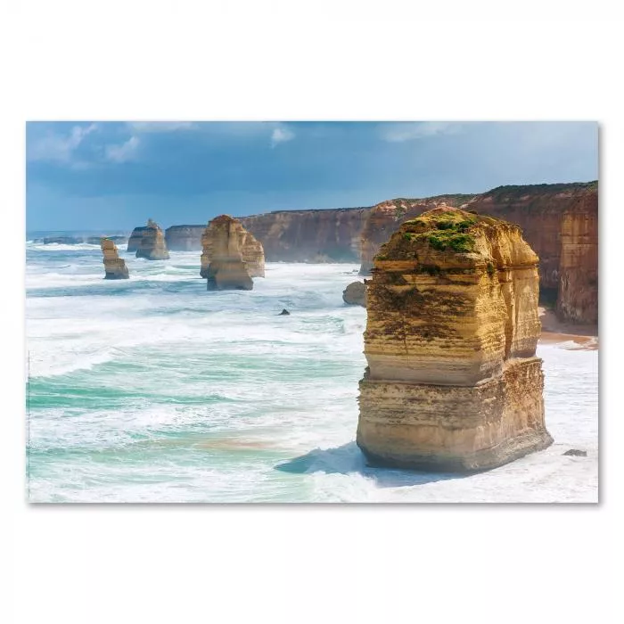 Beeindruckende Steinformationen der Twelve Apostles vor der Küste Australiens, tosende Wellen im Vordergrund.