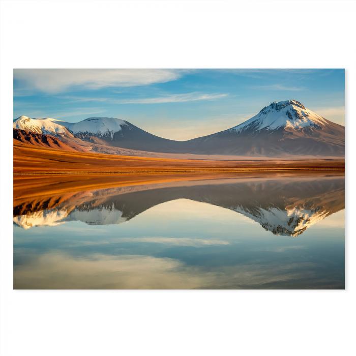 Zwei schneebedeckte Vulkane, orange leuchtender See, Spiegelung, blauer Himmel.