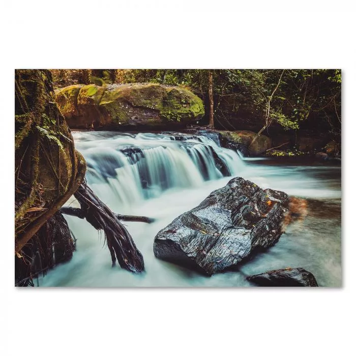 Ein Wasserfall stürzt über Felsen inmitten eines grünen Dschungels. Das klare Wasser funkelt im Licht & erzeugt eine magische & erfrischende Atmosphäre.