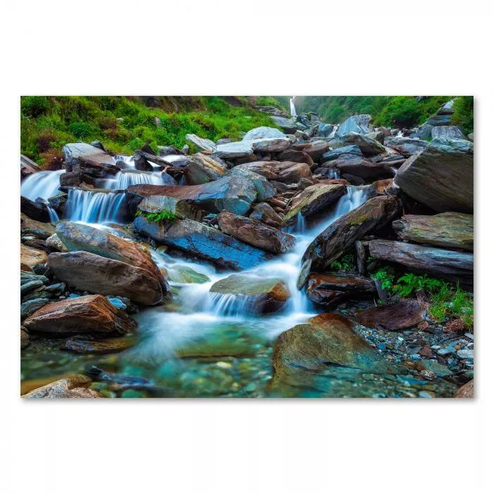 Wasserfall über moosbewachsene Steine, grüne Berglandschaft, idyllische Atmosphäre.