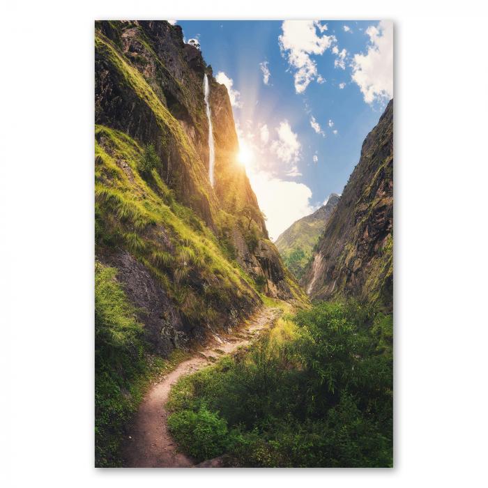 Wasserfall stürzt an Felswand in die Tiefe, Wanderweg durch grüne Landschaft.