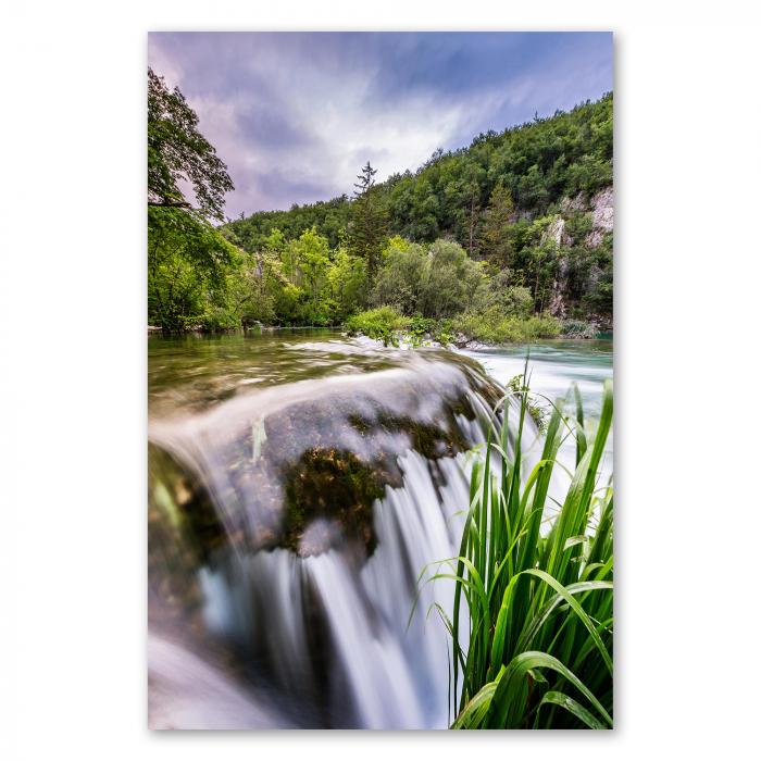 Wasserfall über bemooste Steine, grüner Wald, Gischt - erfrischende Atmosphäre.