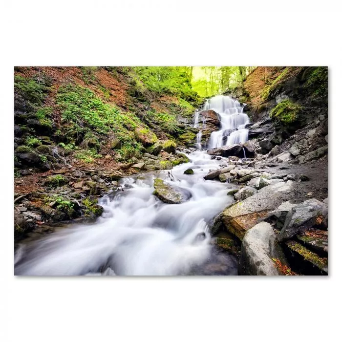 Rauschender Wasserfall stürzt über Felsen, grüner Wald, Sonnenlicht.