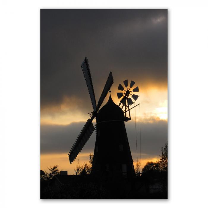 Silhouette einer Windmühle vor dramatischem Abendhimmel mit rot-orangen Wolken und untergehender Sonne.