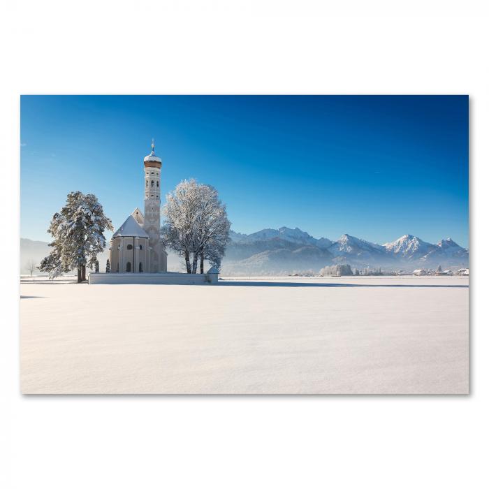 Eine einsame Kirche inmitten einer tiefverschneiten Winterlandschaft – ein Bild von Ruhe und Besinnlichkeit.